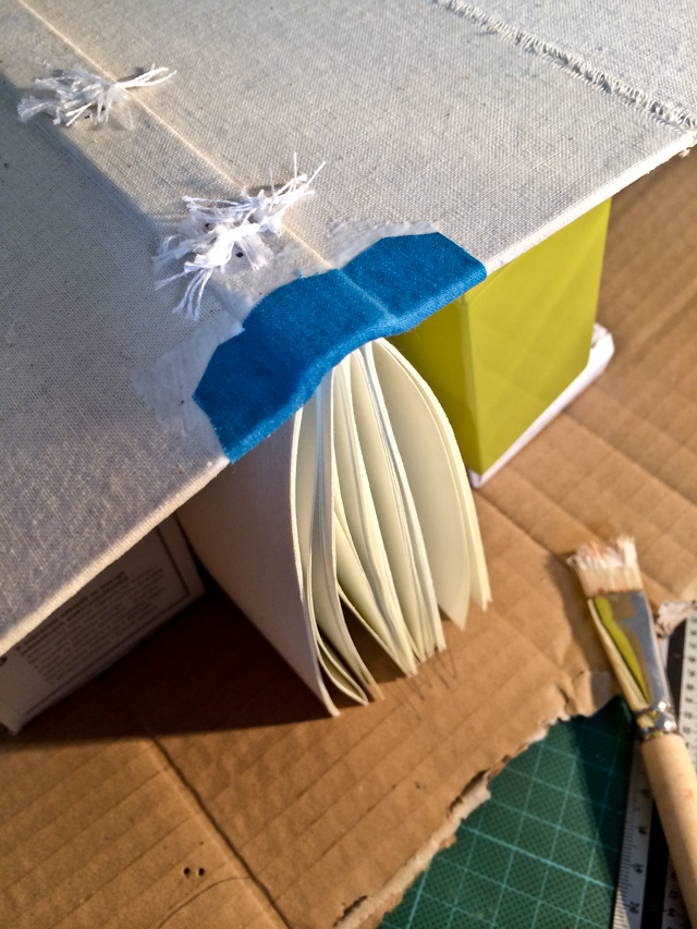 Die Hefte sind im Buchrücken eingenäht, die blaue Verzierung trocknet.